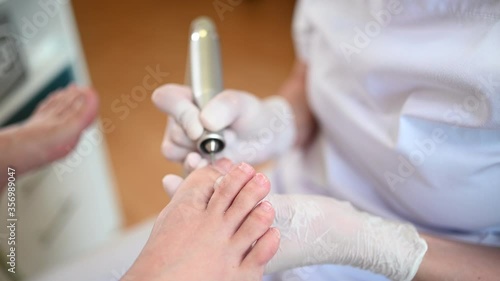Hardware medical pedicure with nail file drill apparatus. Patient on pedicure treatment with pediatrician chiropodist. Foot peeling treatment at spa with a special device. Clinic of Podiatry Podology. photo