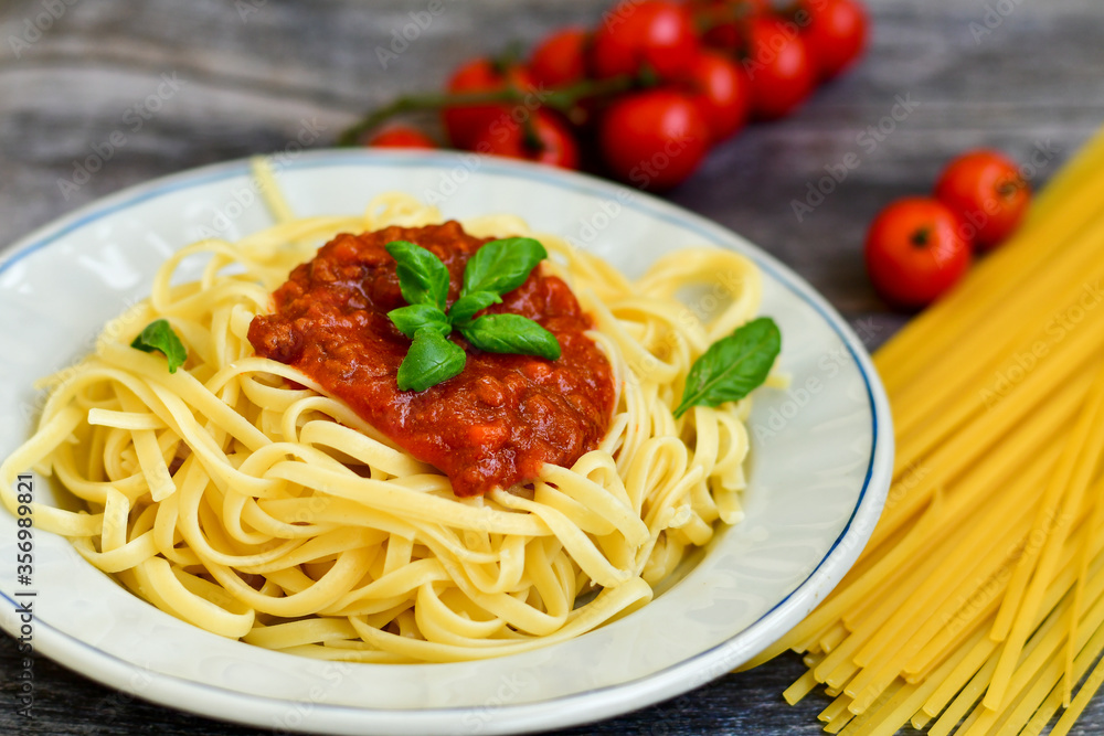 Spaghetti  bolognese .Italian home made meal Fresh  bucatini pasta with tomato sauce, basil, herbs ,parmesan cheese ,fresh cherry tomatoes and parsley on wooden background. Kitchen Poster 