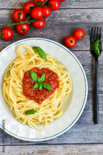 Spaghetti bolognese .Italian home made meal Fresh bucatini pasta with tomato sauce, basil, herbs ,parmesan cheese ,fresh cherry tomatoes and parsley on wooden background. Kitchen Poster 