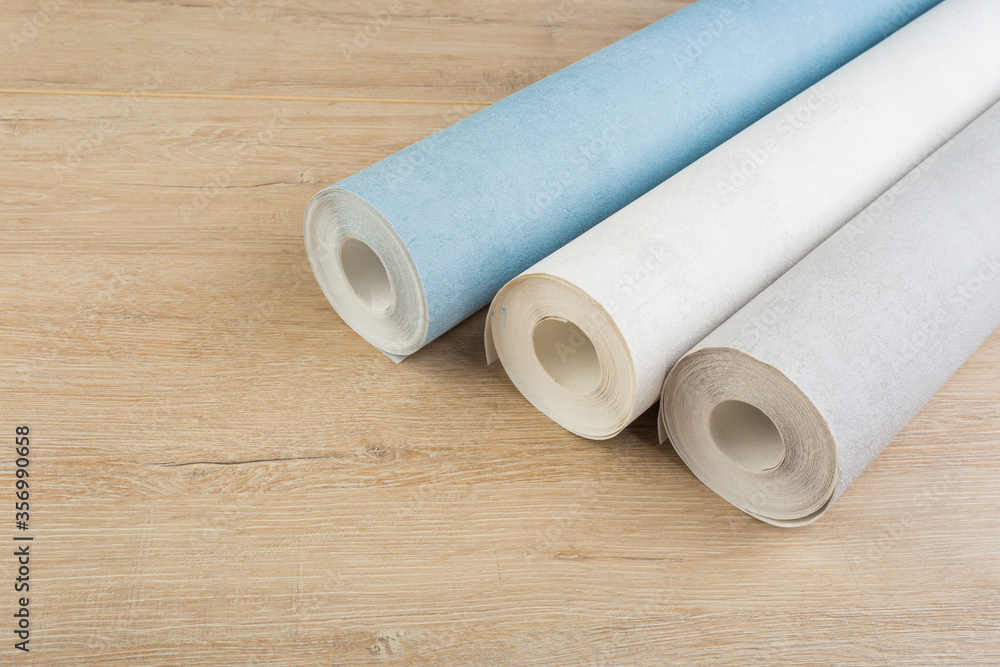 rolls of multi-colored paper wallpaper on a wooden table rolls of multi-colored paper wallpaper on a wooden table