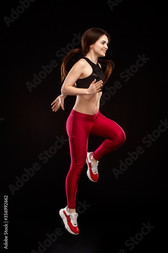 young, slim girl, in sportswear, jumping, isolated on a black background