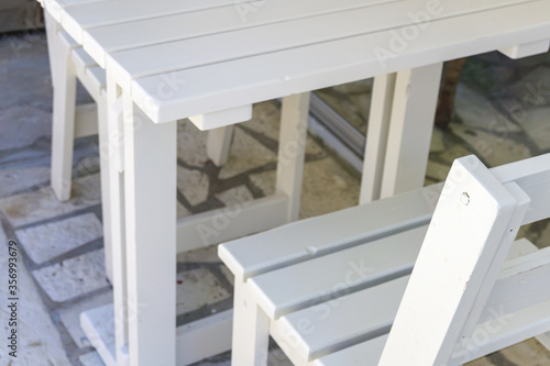 Close up set of white wooden chair and table at patio. Rustic design, interior detail. Simple comfortable furniture.