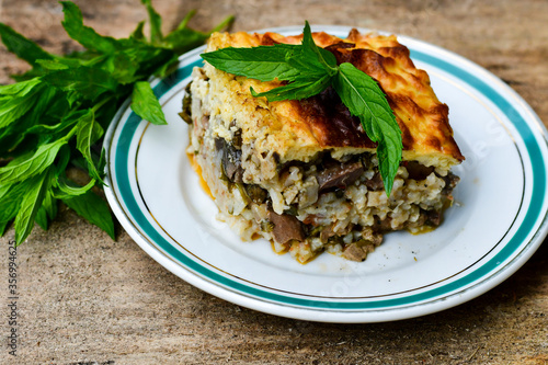Casserole with rice and cheese pie with lamb meat and mint . Rustic background. 