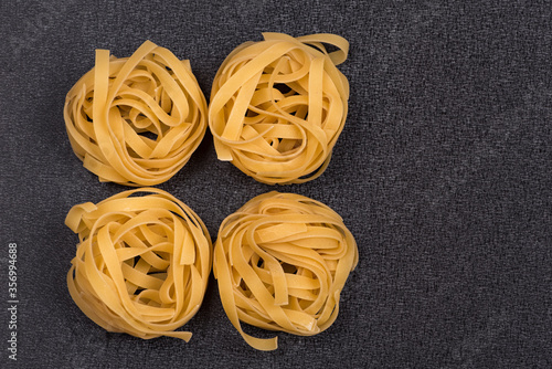 Fettuccine or Tagliatelle on gray background. Spaghetti nests. Italian cuisine. Dry uncooked pasta