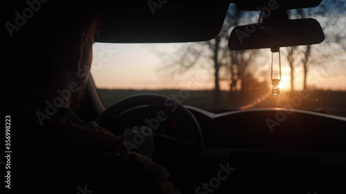 a young man goes behind the wheel at sunset