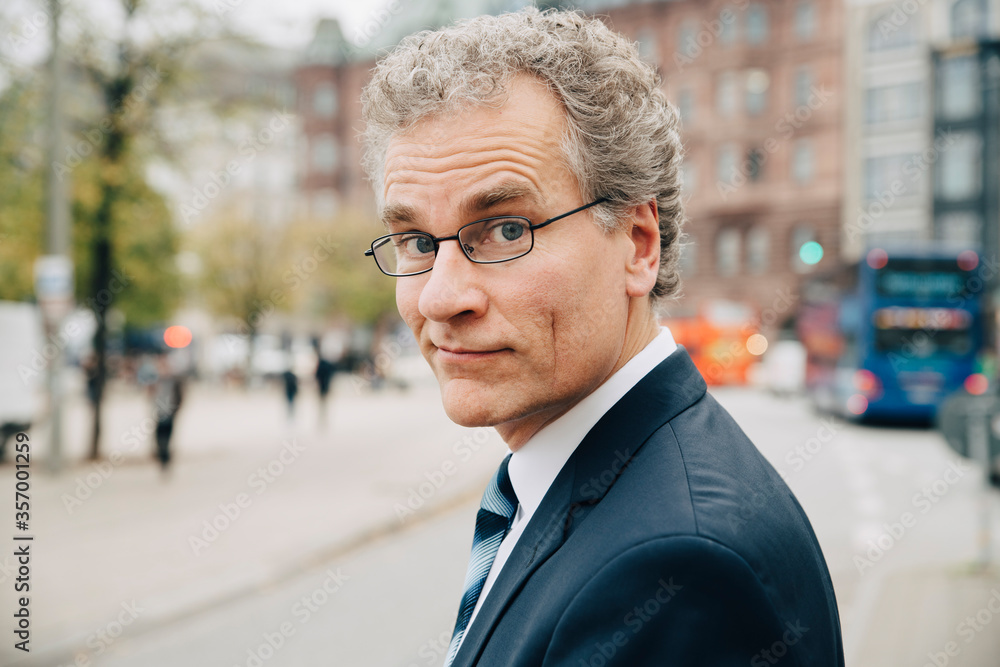 Portrait of smiling businessman wearing suit while standing in city Portrait of smiling businessman wearing suit while standing in city
