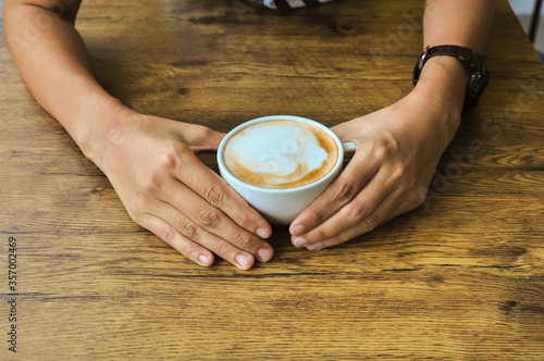 Female hands holding cups of coffee on rustic wooden table background