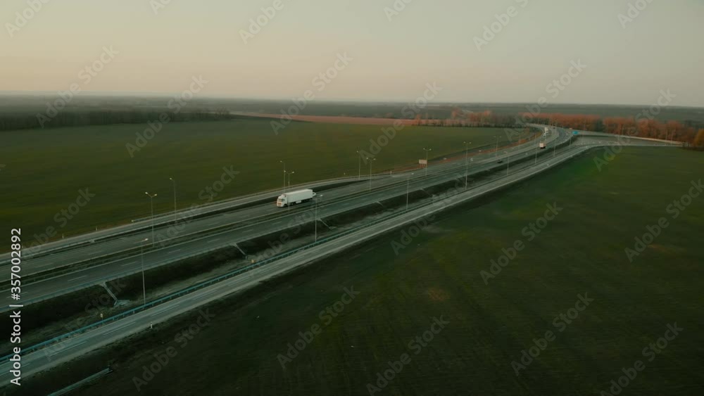 Aerial shot of a truck on the road out of town on the highway on evening sunset Aerial shot of a truck on the road out of town on the highway on evening sunset