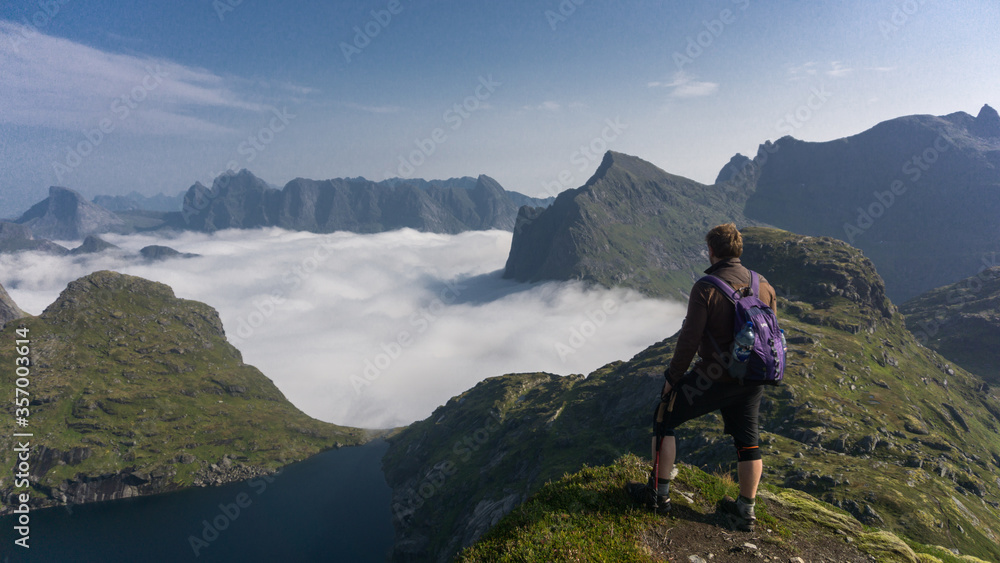 Lofoten isnalds, Norway hiking - Man hiking in pristine mountains above the clouds