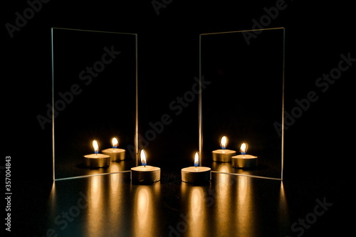 burning candle and mirror on a black background. reflection of a candle flame in a mirror in the dark photo