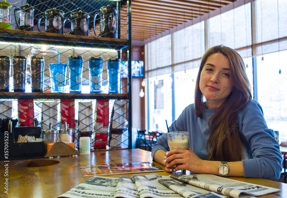 A girl is drinking coffee in a coffee house.

