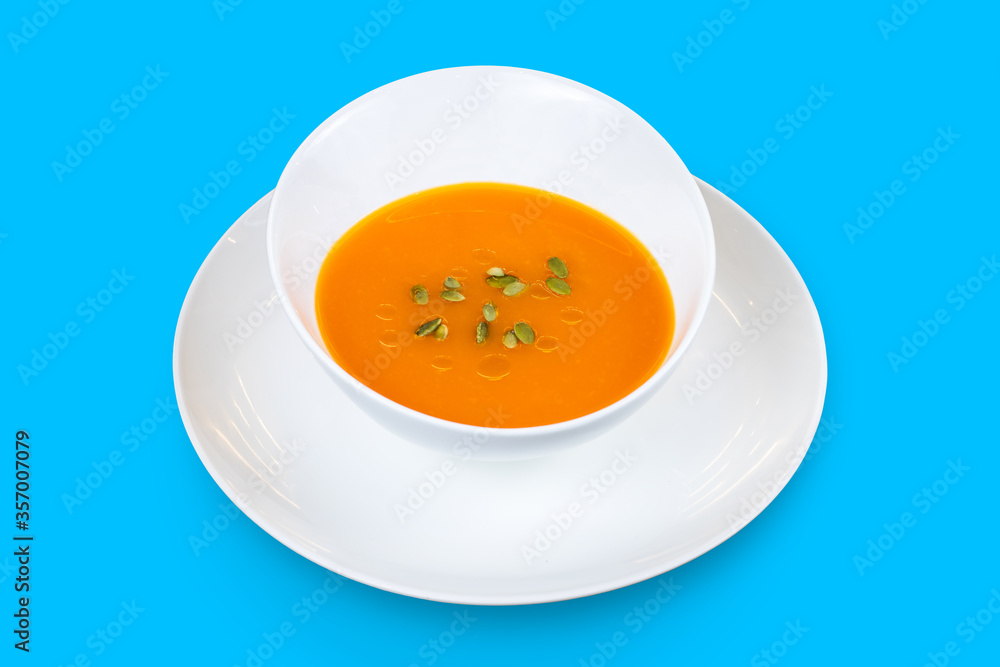 Pumpkin cream soup with seeds isolated on a blue background Pumpkin cream soup with seeds isolated on a blue background