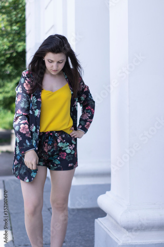 Attractive young brunette woman in yellow t-shirt and flowery shorts costume. copy space. High quality photo