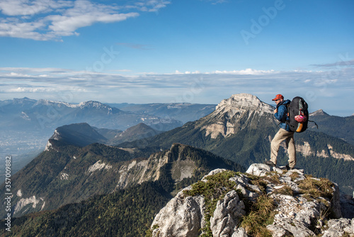 Young man standing on the top of a mountain overlooking a beautiful view © Ezan