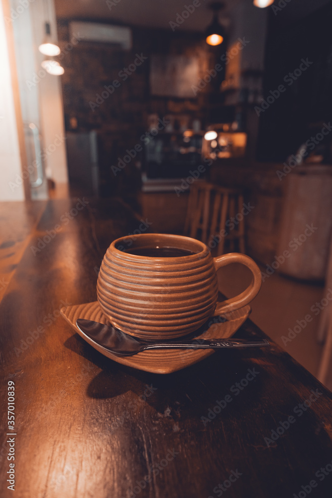 Primero plano café en vaso de barro dentro de una cafetería solo en vertical