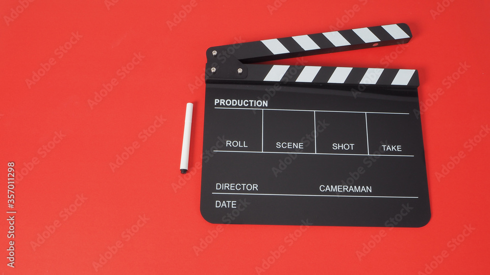 Pen with black Clapperboard or movie slate use in film production and cinema industry on red background.