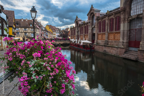 The beautiful navigable canal of Colmar, in Alsace, France covered in its margins and its bridges, with flowers,