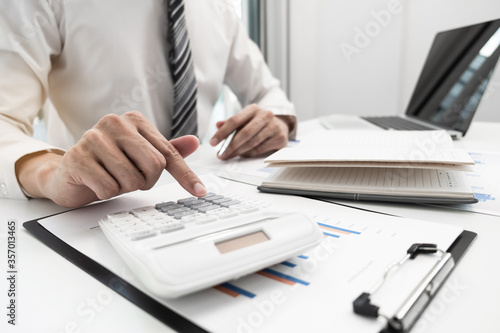 Fototapeta Naklejka Na Ścianę i Meble -  Businessman using calculator for calculate business income in the office room.