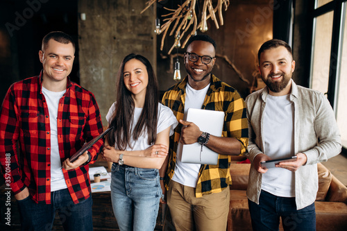 Group business portrait. Portrait of young successful multiethnical employees dressed in stylish casual wear standing in their modern creative office with a friendly atmosphere