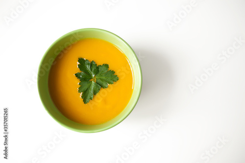 pumpkin cream soup for lunch in a green plate on a white table