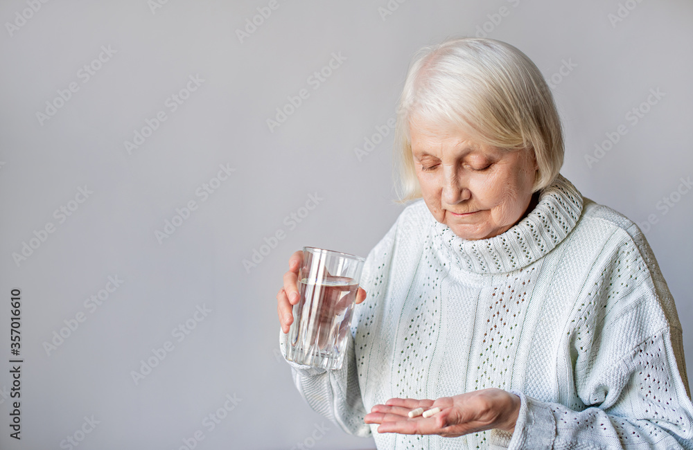 gray-haired elderly senior holding a tablet and a glass of water gray-haired elderly senior holding a tablet and a glass of water