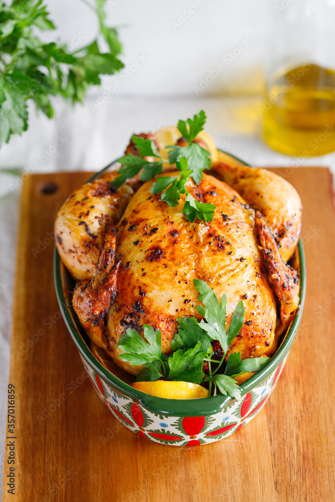 Whole roasted chicken with fresh parsley and lemon wedges in a festive dish Whole roasted chicken with fresh parsley and lemon wedges in a festive dish