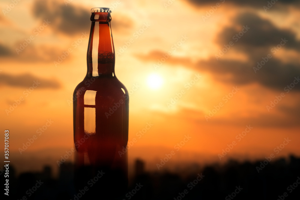 Beer bottle over a bokeh red sky background. Beer bottle over a bokeh red sky background.