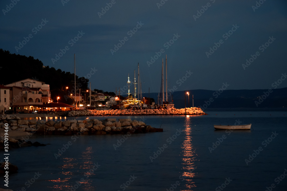 Calm and warm summer night the seacoast in Croatia with lights reflecting in the water.