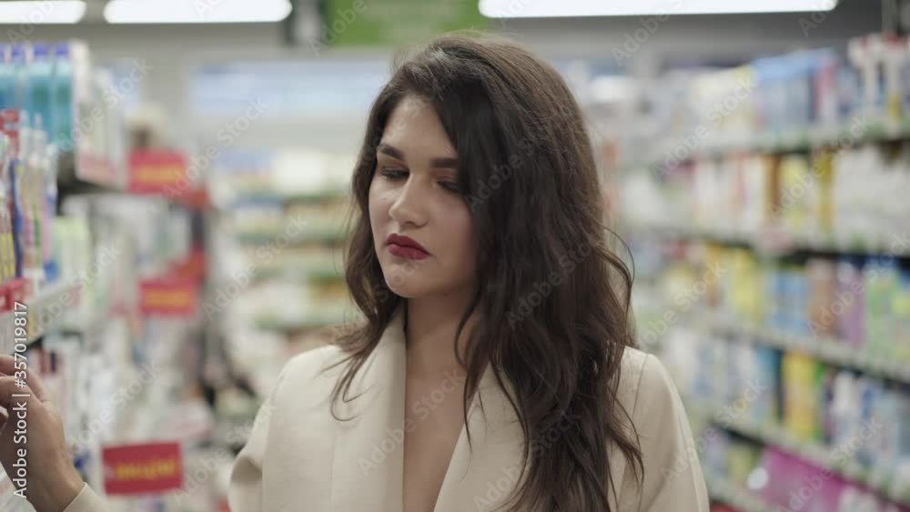 Portrait of thoughtful pretty woman examines goods on the supermarket shelves Portrait of thoughtful pretty woman examines goods on the supermarket shelves