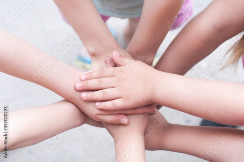 Children's hands are folded on top of each other. Symbol of unity and teamwork.