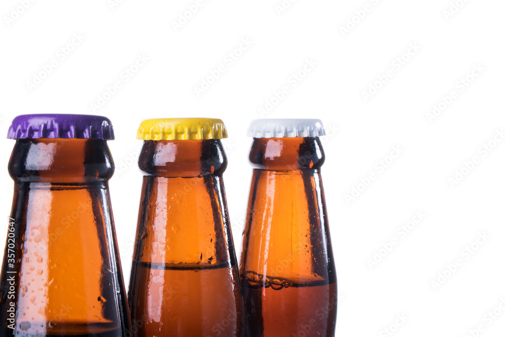 Brown beer bottles over white background. Beer with colored caps. Close up view of drinks with copy space. Brown beer bottles over white background. Beer with colored caps. Close up view of drinks with copy space.