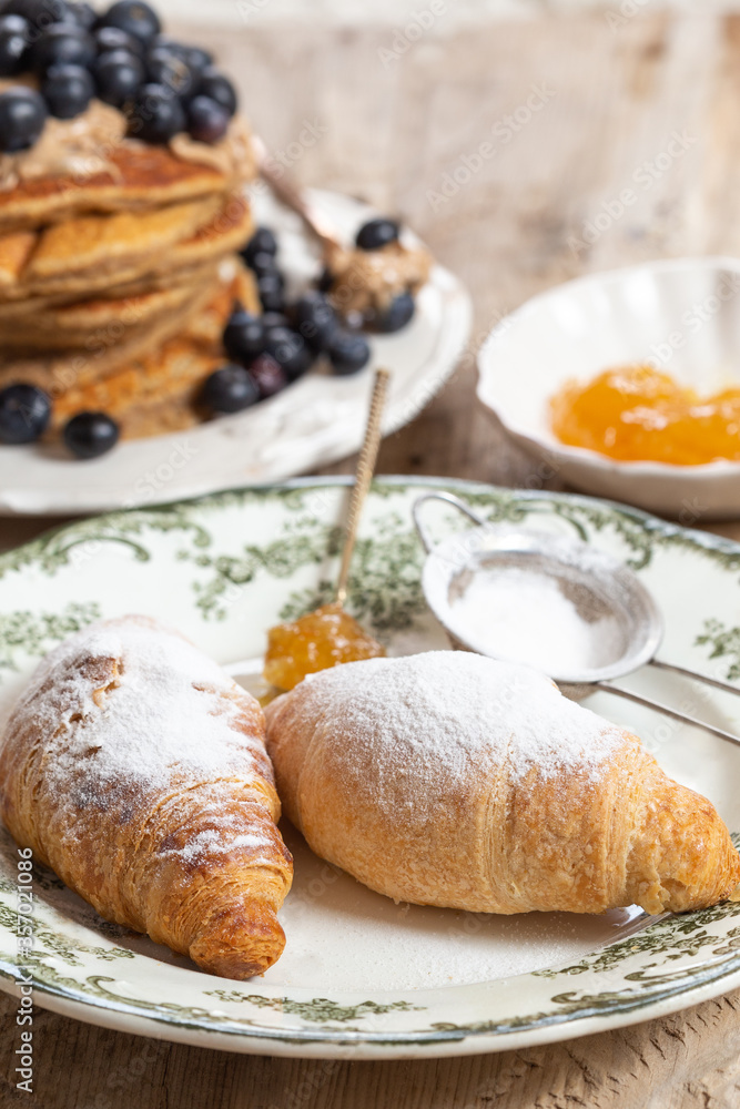 Two croissants in a ceramic plate with green pattern Two croissants in a ceramic plate with green pattern