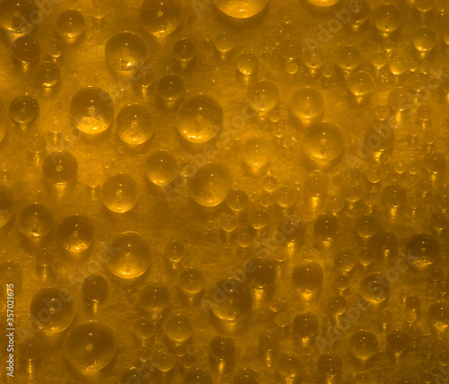 Abstract yellow-red background of drops and droplets. Close up. Illuminated by the bright sun yellow-red drops of water are located on a glass surface.