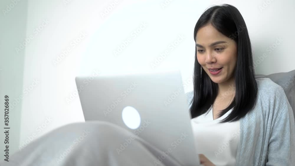Work from home concept.Smiley asian businesswoman working on laptop computer in the bed room and feel good. Slow Motion Full Hd. Work from home concept.Smiley asian businesswoman working on laptop computer in the bed room and feel good. Slow Motion Full Hd.