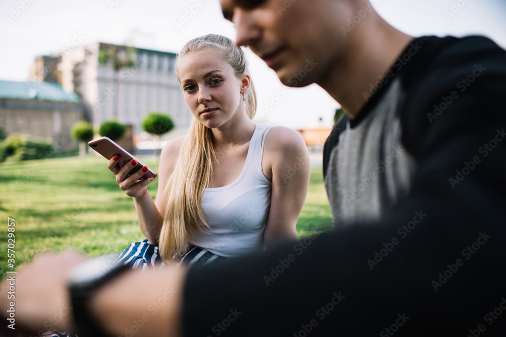 Serious woman with phone in park with friend