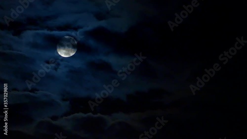Full moondown through the clouds on dark blue night sky. 1 Minute, 30 fps footage of 4K timelapse moonscape
