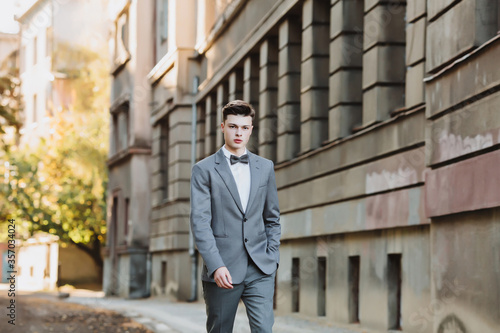 A businessman in an elegant suit with a bow tie walks along the street. Place for text. on the way to the robot. Career.