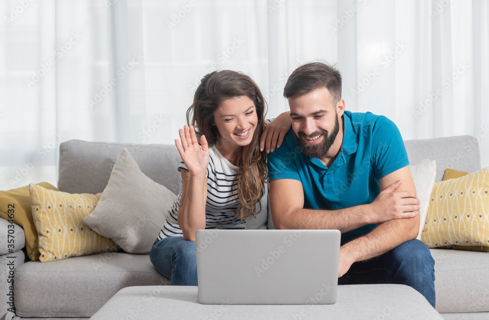 Young couple man and woman talking online over the laptop to her parents first time from their new apartment after they finally moved out from his parents house Young couple man and woman talking online over the laptop to her parents first time from their new apartment after they finally moved out from his parents house