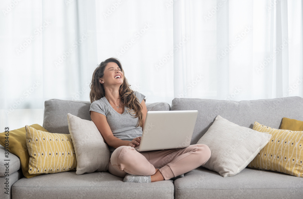 Young beautiful single woman chatting with her boyfriend or girlfriend on the laptop computer siting on the sofa and laugh with big smile Young beautiful single woman chatting with her boyfriend or girlfriend on the laptop computer siting on the sofa and laugh with big smile