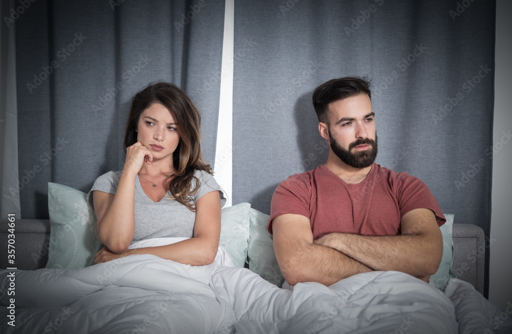 Young man and woman, boyfriend and girlfriend lying in the bed in the silence and not talking after they had a fight and argue about her money spending on new clothes Young man and woman, boyfriend and girlfriend lying in the bed in the silence and not talking after they had a fight and argue about her money spending on new clothes