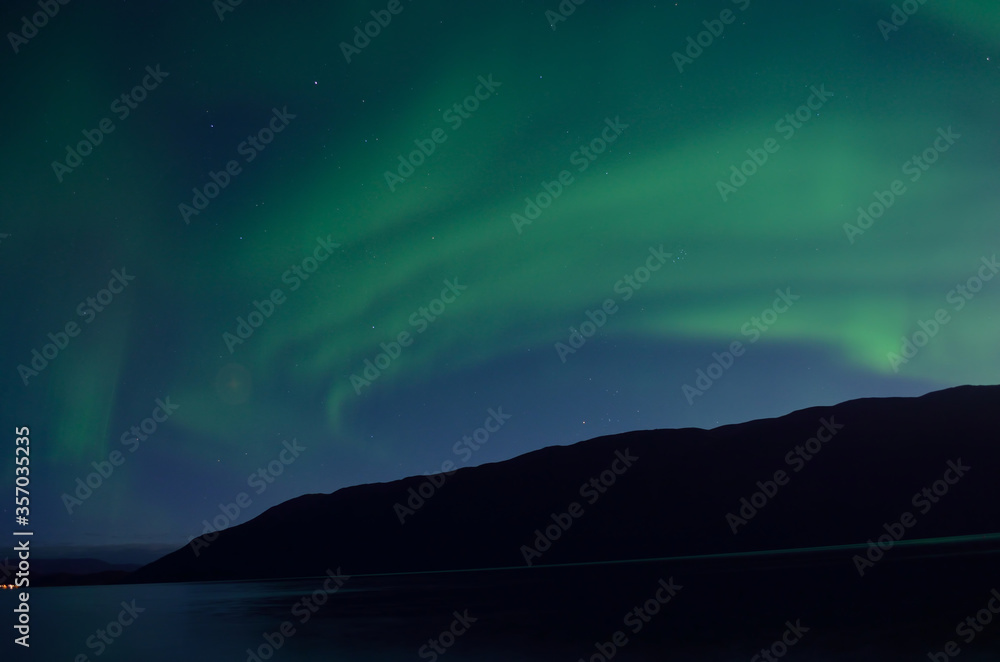 majestic aurora borealis dancing over mountain island and fjord in autumn night