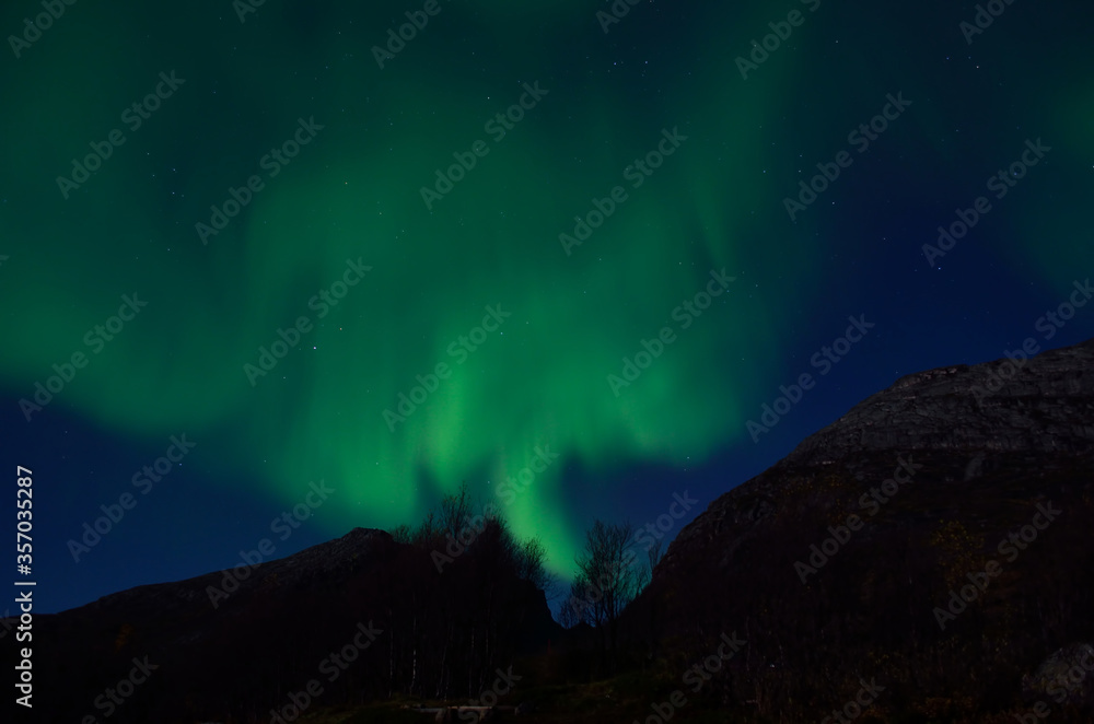 massive aurora borealis dancing on night sky over mountain in northern Norway massive aurora borealis dancing on night sky over mountain in northern Norway