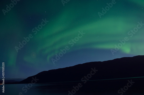 majestic aurora borealis dancing over mountain island and fjord in autumn night