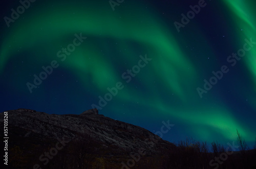 massive aurora borealis dancing on night sky over mountain in northern Norway © Arcticphotoworks