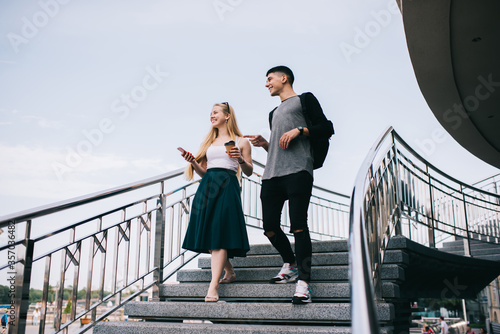 Young cheerful couple walking down stair in city