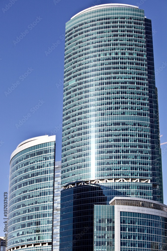 Fototapeta premium Office and residential skyscrapers on bright sun and clear blue sky background. Commercial real estate. Modern business city district. Office buildings exterior. Financial city district. Downtown.