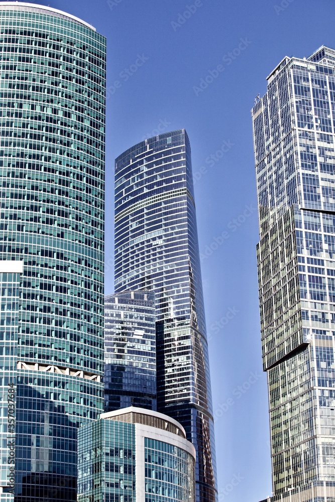 Obraz premium Office and residential skyscrapers on bright sun and clear blue sky background. Commercial real estate. Modern business city district. Office buildings exterior. Financial city district. Downtown.