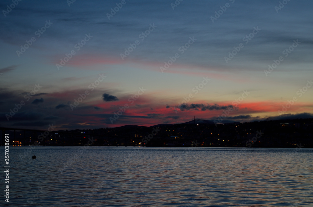 pink and colorful dawn sky over the tromsoe city island with reflection on the blue fjord surface pink and colorful dawn sky over the tromsoe city island with reflection on the blue fjord surface