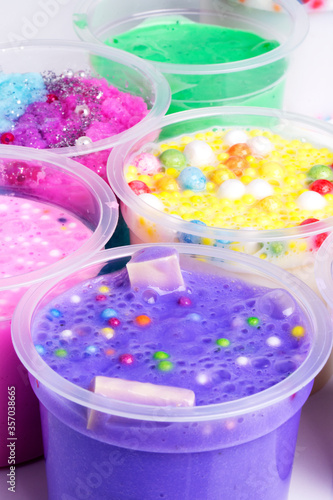 Various bows of colored slime with colorful dots over light gray background.
