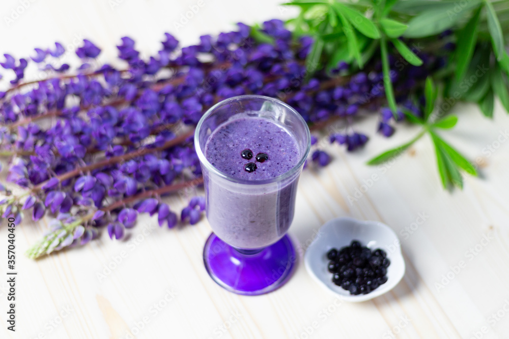 glass of fresh banana and blueberry smoothie and purple lupine flowers on wooden table glass of fresh banana and blueberry smoothie and purple lupine flowers on wooden table